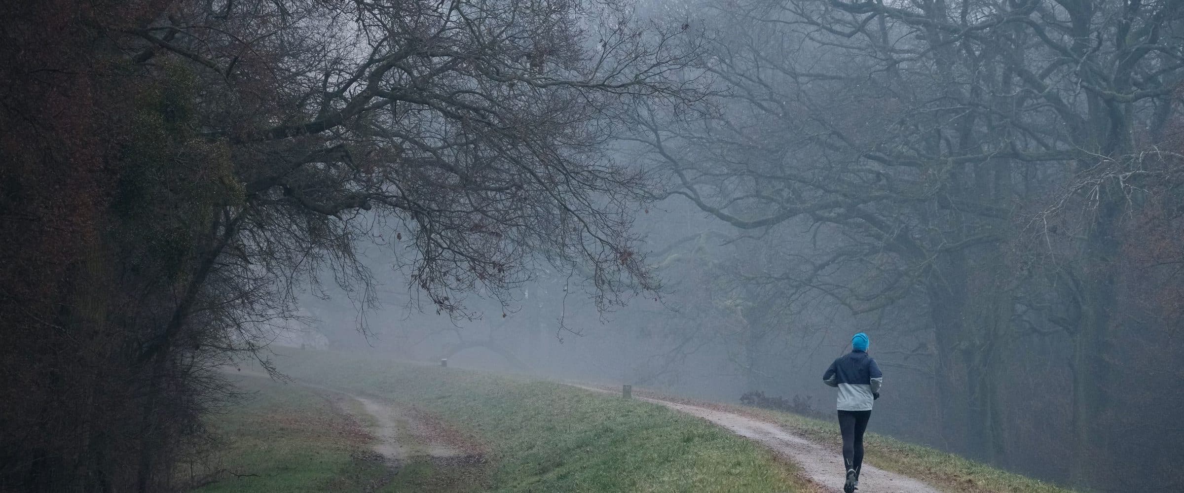Coureur sur un chemin forestier dans la brume